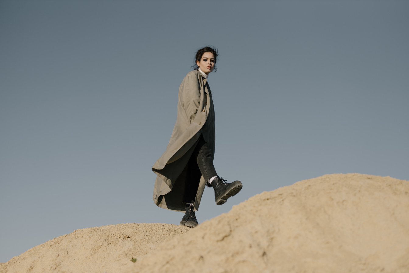 Man in Black Coat Sitting on Brown Rock